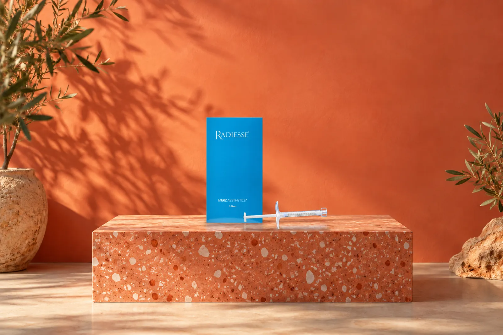 Caja de Radiesse con una jeringa tumbada sobre una base de terrazo